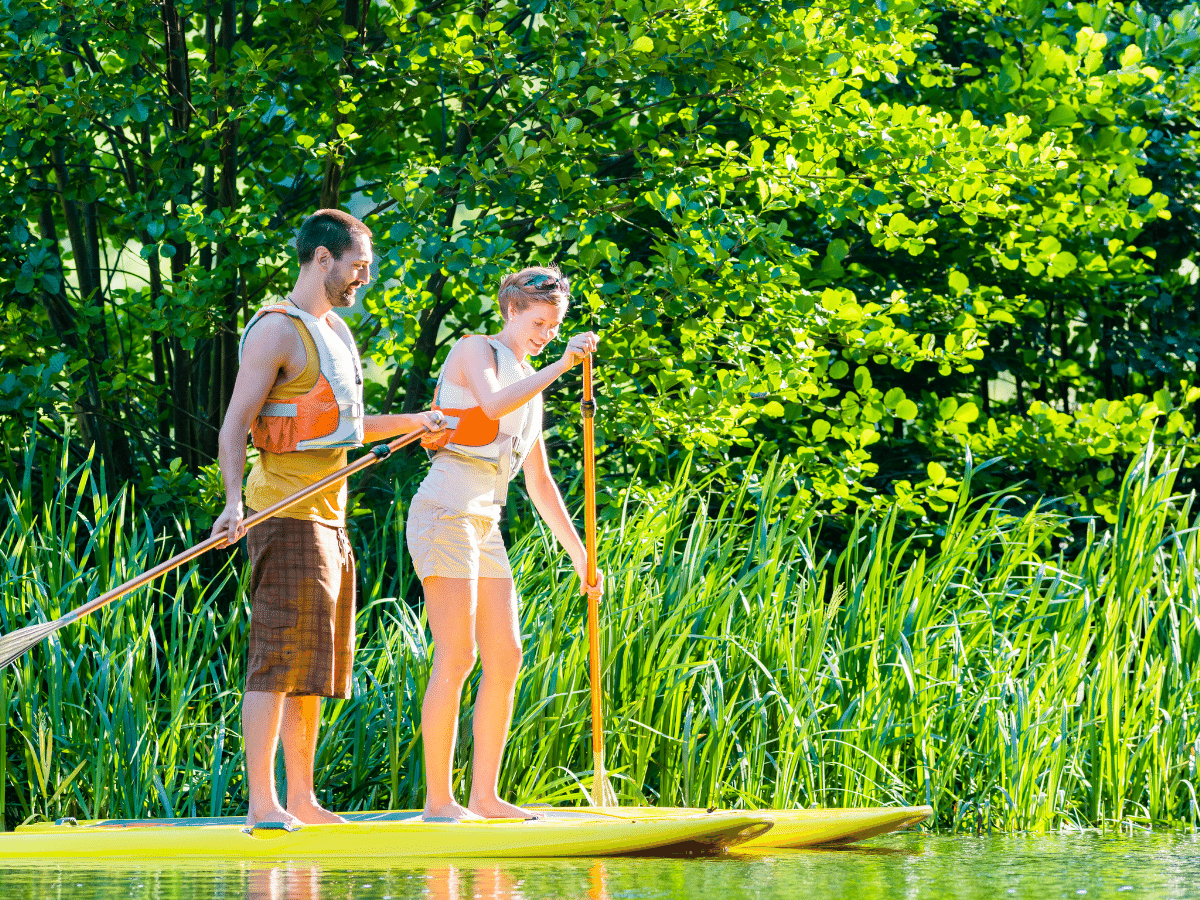 Couple paddle boarding through the city countryside