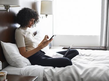 Woman texting on her phone sitting on the bed