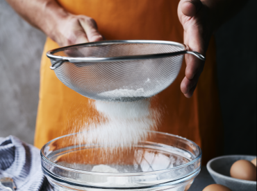 Man in apron sieving flour